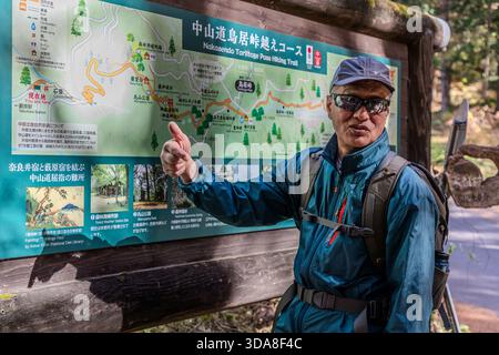 Ein Wanderführer zeigt auf die Routenkarte des Nakasendo Toriitoge Pass Trail (中山道鳥居峠越えコース) im Kiso-Tal, Präfektur Nagano, Japan. Dieser historische Bergpass verbindet die Poststationen Narai-juku und Yabuhara-juku Stockfoto