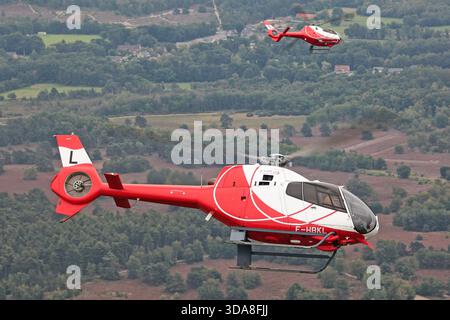 Luftbild von zwei HeliDax Eurocopter EC-120B Colibri Hubschraubern, Zulassungen F-HBKL und F-HBKN, die während der Sanicole Air Show in Belgien 2019 flogen. Das Foto zeigt beide Rotorboote im selben Bild. Stockfoto