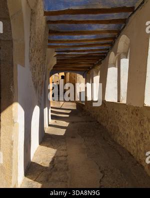 Mittelalterliche überdachte Straße in Miravet mit Steinbögen, Holzbalken und Kopfsteinpflasterboden in Katalonien, Spanien. Stockfoto