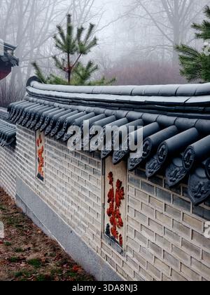 Traditionelle koreanische Mauer im Nebel. Traditionelle koreanische Steinmauer an einem nebeligen Morgen. Die obere Abdeckung besteht aus halbzylindrischen Giwa-Fliesen. Stockfoto