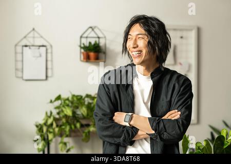 Junge asiatische Blumenhändler lächeln in einem lebhaften Geschäft, umgeben von Pflanzen und Blumen. Stockfoto