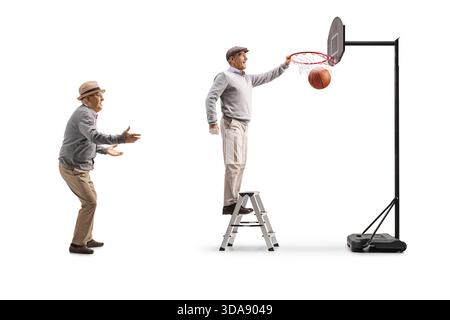 Fröhliche ältere Männer spielen Basketball und klettern auf einer Leiter, um isoliert auf weißem Hintergrund zu Punkten Stockfoto