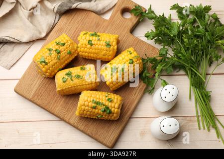 Stücke gekochter Maiskolben mit Petersilie auf Holztisch, flache Lagen Stockfoto