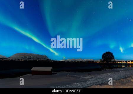 Leuchtend grüne Nordlichter leuchten über Tromsø, Norwegen, und werfen fließende aurorafuhren über den arktischen Nachthimmel Stockfoto