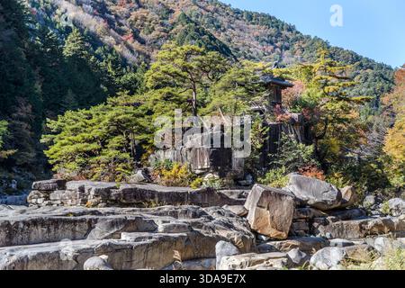 Auf einem felsigen Plateau mit Blick auf den Fluss Kiso steht neben einer Steinlaterne eine knorrige Kiefer – eine charakteristische Landschaftskomposition in Nezame-no-Toko, Agematsu, Präfektur Nagano, Japan Stockfoto