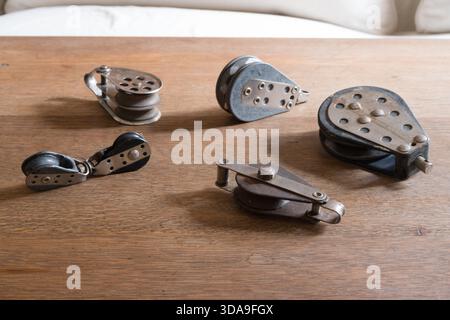 Sammlung von Vintage-Segelblöcken aus Metall und Holz mit einer kleinen einzelnen Riemenscheibe auf einem Holztisch Stockfoto