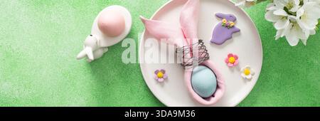 Ein wunderschön gestalteter Tisch für Ostern verfügt über eine rosa Serviette, die um ein Ei gewickelt ist, umgeben von Blumendekorationen und bunten Süßigkeiten, b Stockfoto