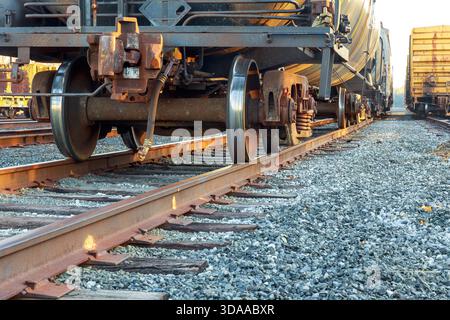 Die Räder der Züge ruhen auf Gleisen auf dem Bahnhofsgelände in der Nähe von Industriegebäuden Stockfoto