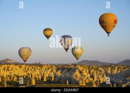 Verschiedenfarbige Ballons schweben im goldenen Licht über eine felsige Landschaft, Heißluftballons, Goereme Nationalpark, Goereme Tarihi Milli Park, Nevsehi Stockfoto