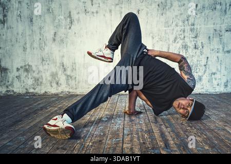 Junger Mann, der auf Wandhintergrund tanzt. Tätowierung am Körper Stockfoto