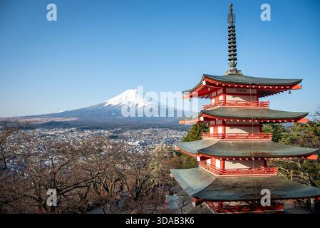 Chureito-Pagode und schneebedeckter Fuji-Berg oberhalb von Fujiyoshida. Rote fünfstöckige Pagode neben dem Vulkankegel von Fuji über der Stadt an einem klaren Wintertag. Stockfoto