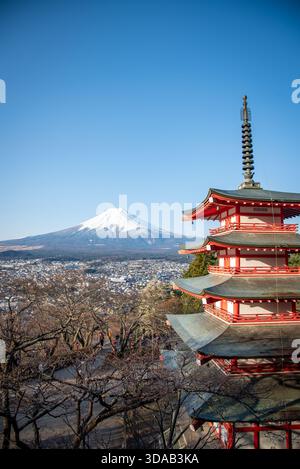 Chureito-Pagode mit Fuji und Fujiyoshida unten. Vertikale Komposition, die die rote Pagode neben dem schneebedeckten Fuji mit Blick auf die Stadt zeigt. Stockfoto