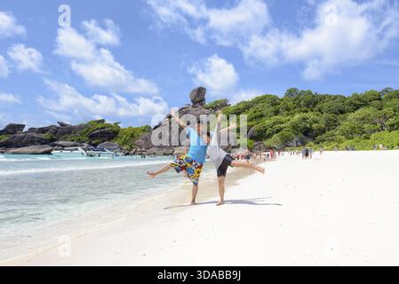 Das Touristenpaar hob seine Arme und Beine mit Happy am Strand in der Nähe des Meeres unter blauem Himmel und Wolke des Sommers auf Koh Similan Island in Mu Ko Similan Nat Stockfoto
