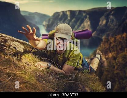 Junger Mann touristischen Überlebenden vom hohen Berg fallen und versucht zu erklimmen Stockfoto
