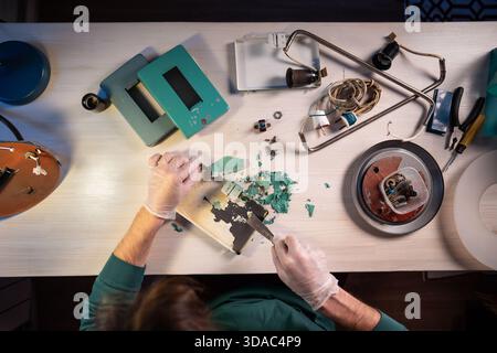 Handwerker mit Spachtelmesser und präzises Abkratzen trockener Lackschichten vom Innern des Grundteils. Stockfoto
