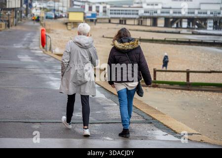 Zwei Frauen, die im Winter entlang eines Küstenweges an der Küste der isle of wight UK spazieren und sprechen Stockfoto