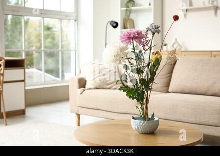 Topf mit wunderschönem Ikebana auf Couchtisch in stilvollem Wohnzimmer, Nahaufnahme Stockfoto