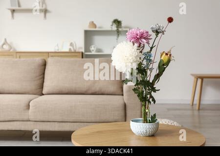 Topf mit wunderschönem Ikebana auf Couchtisch in stilvollem Wohnzimmer, Nahaufnahme Stockfoto