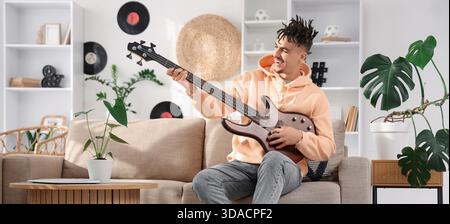 Junger Mann mit Dreadlocks, der zu Hause elektrische Gitarre spielt Stockfoto