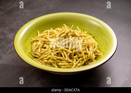 Trofie-Pasta mit grüner Pesto-Sauce in einer hellgrünen Schüssel, die italienische kulinarische Tradition repräsentiert Stockfoto