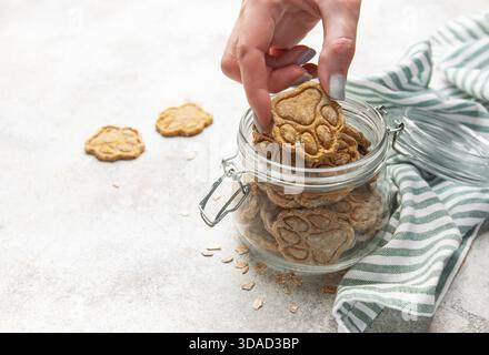 Frau Hand nimmt ein Pfotenmuster Haustier Leckerli aus einem Glas Stockfoto