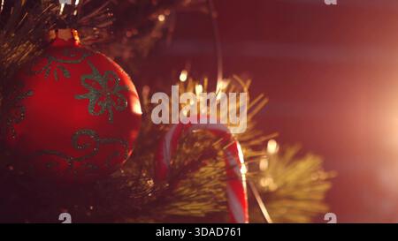 Flaches Weihnachtsdesign zeigt rote Kugel mit grünem Glitzer und Zuckerrohr auf Kiefernnadeln Stockfoto