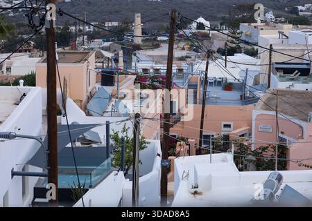 Santorini, Griechenland - 1. November 2025. Stromleitungen und Holzmasten dominieren die Dachszene auf Santorin Stockfoto