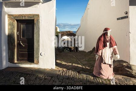 Monsaraz, Portugal - 07. Dezember 2024: Eine Seitenstraße und Gasse in Monsaraz, Portugal, mit einer Figur aus einer Krippe im Freien. Stockfoto