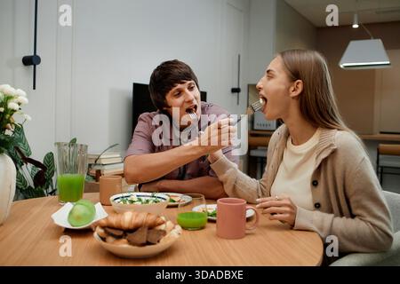 Junger Mann Füttert Junge Frau Beim Gemeinsamen Frühstück Stockfoto