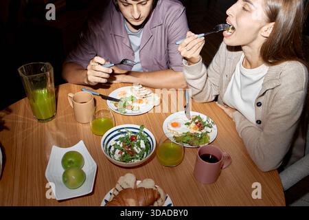 Junger Mann und Frau essen zusammen am Holztisch Stockfoto
