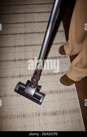 Frau saugt Teppich zu Hause mit Upright Cleaner Stockfoto