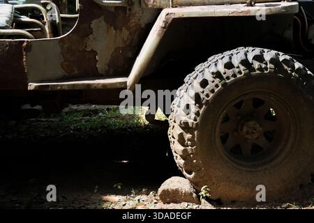 Nahaufnahme des dreckigen Militärwagenrads auf rauem Gelände. Matschige Reifen und Tarnmuster dieses leistungsstarken Geländefahrzeugs deuten auf eine Extravaganz hin Stockfoto