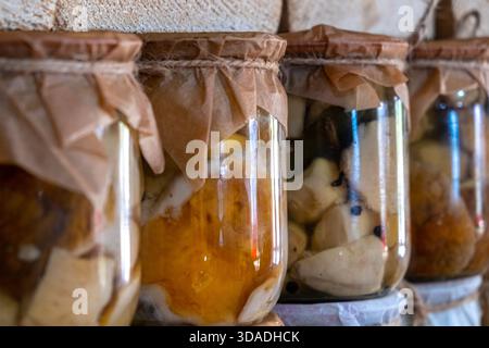 In der Nahaufnahme von Glasgläsern ist ein Regal mit handgemachten Dosenpilzen zu sehen. Laden von landwirtschaftlichen Produkten in den ukrainischen Karpaten. Stockfoto