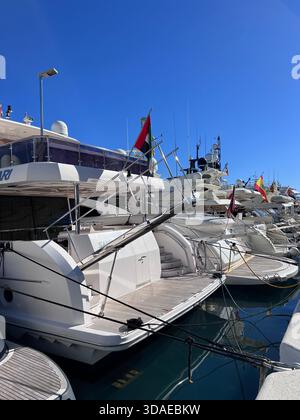 Luxusyachten und -Flaggen, die unter einem klaren blauen Himmel am Jachthafen Puerto Banus in Marbella, Spanien, vertäut sind. Stockfoto