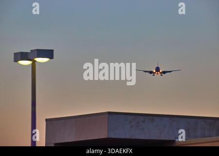 Flugzeug nähert sich der Landung in der Abenddämmerung mit Gebäude und Straßenlaterne in Las Vegas Stockfoto