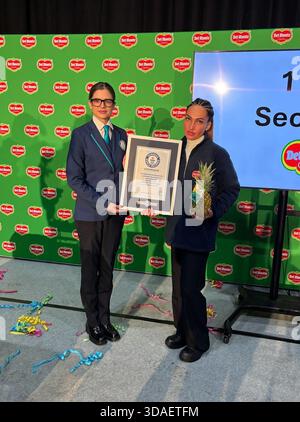 Dominika Gasparova, 35 Jahre alt, mit der offiziellen Schiedsrichterin Joanne Brent, die in 11,43 Sekunden eine Ananas schälte und in Scheiben geschnitten hat - und jetzt Titelhalter des Guinness World Records ist. Der erfolgreiche offizielle Versuch war in der Fabrik Del Monte in Wisbech, Cambridgeshire, wo sie arbeitet. Bilddatum: Mittwoch, 10. Dezember 2025. Stockfoto