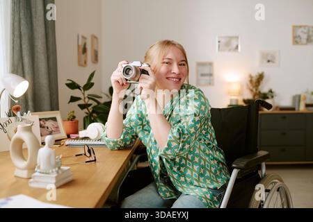 Porträt einer jungen erwachsenen Frau im Rollstuhl, die Kamera lächelnd hält Stockfoto