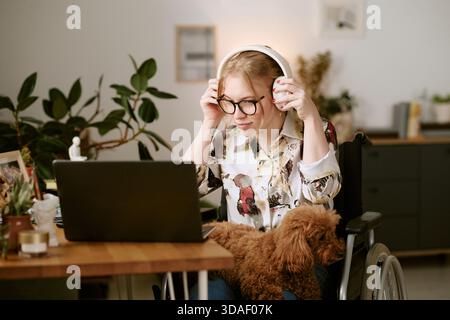 Junge Frau mit Behinderung mit Laptop und Musikhören Stockfoto