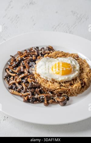 Das gemütliche Reisgericht besteht aus Butterpilzen, Sesamgarnitur und perfekt gekochtem Eigelb Stockfoto