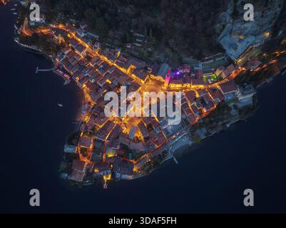 Blick aus der Vogelperspektive auf das Dorf am Rande des Sees, Lichter funkeln wie Sterne vor dem tiefblauen Wasser, Varenna, Lombardia, Italien. Stockfoto
