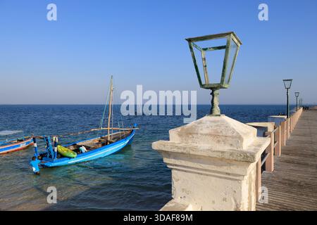 Fischer laden Vorräte zu einer Dau am historischen und rustikalen Hauptpier von Stone Town auf der Insel Mosambik, Mosambik Stockfoto
