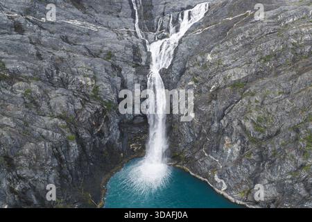 Aus der Vogelperspektive eines mächtigen Wasserfalls, der über eine zerklüftete, felsige Klippe in einen ruhigen türkisfarbenen Pool stürzt, Whittier, Alaska, USA. Stockfoto