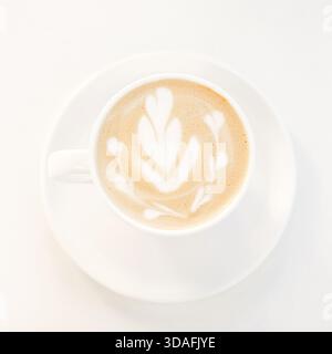 Latte Art in einer weißen Kaffeetasse auf einer Untertasse, minimalistische und gemütliche Frühstücksszene Stockfoto