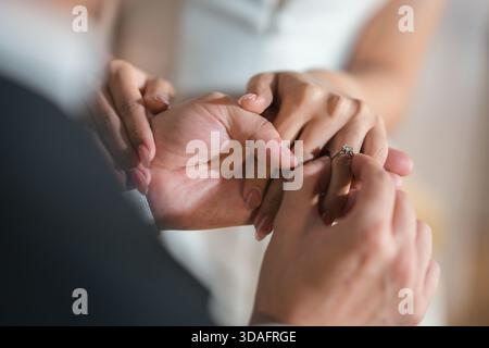 Nahaufnahme der intime Moment, in dem Braut und Bräutigam während der Hochzeitszeremonie Diamantringe austauschen. Symbolisiert auf wundervolle Weise Liebe, Engagement und Stockfoto