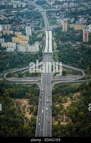 Aus der Vogelperspektive eines weitläufigen Autobahnkreuzes, der durch üppiges Grün und Stadtentwicklung führt, Warschau, Polen. Stockfoto
