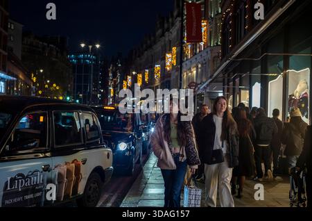 Touristen genießen die Weihnachtsbeleuchtung vor Harrods an der Brompton Road im wohlhabenden Knightsbridge-Viertel im Zentrum von London, England, Großbritannien Stockfoto