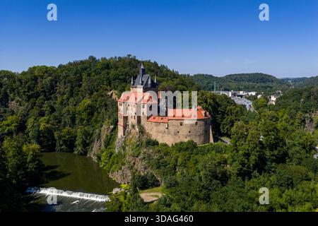 Aus der Vogelperspektive auf die Burg Kriebstein, eine mittelalterliche Burg mit markanten roten Dächern, die auf einem Felsvorsprung inmitten üppiger Vegetation thront, Kriebstein, Sachsen, Germa Stockfoto