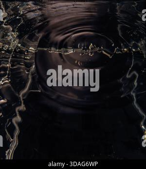 463.Nahaufnahme der Wasseroberfläche mit konzentrischen Wellenringen und Reflexionen bei schwachem Licht.Beleuchtung erzeugt abstrakte Textur und Bewegung. Bildaufnahmen f Stockfoto