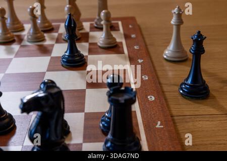 Schachkönigin steht auf der Seite auf einem Schachbrett, geneigtes Stück symbolisiert Instabilität und Strategie, klassisches Brettspiel-Konzept, Stockfoto