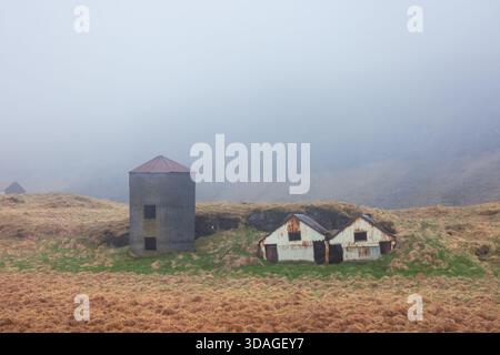Alte isländische Rasenhäuser und Scheune im Nebel in Island gefangen. Stockfoto